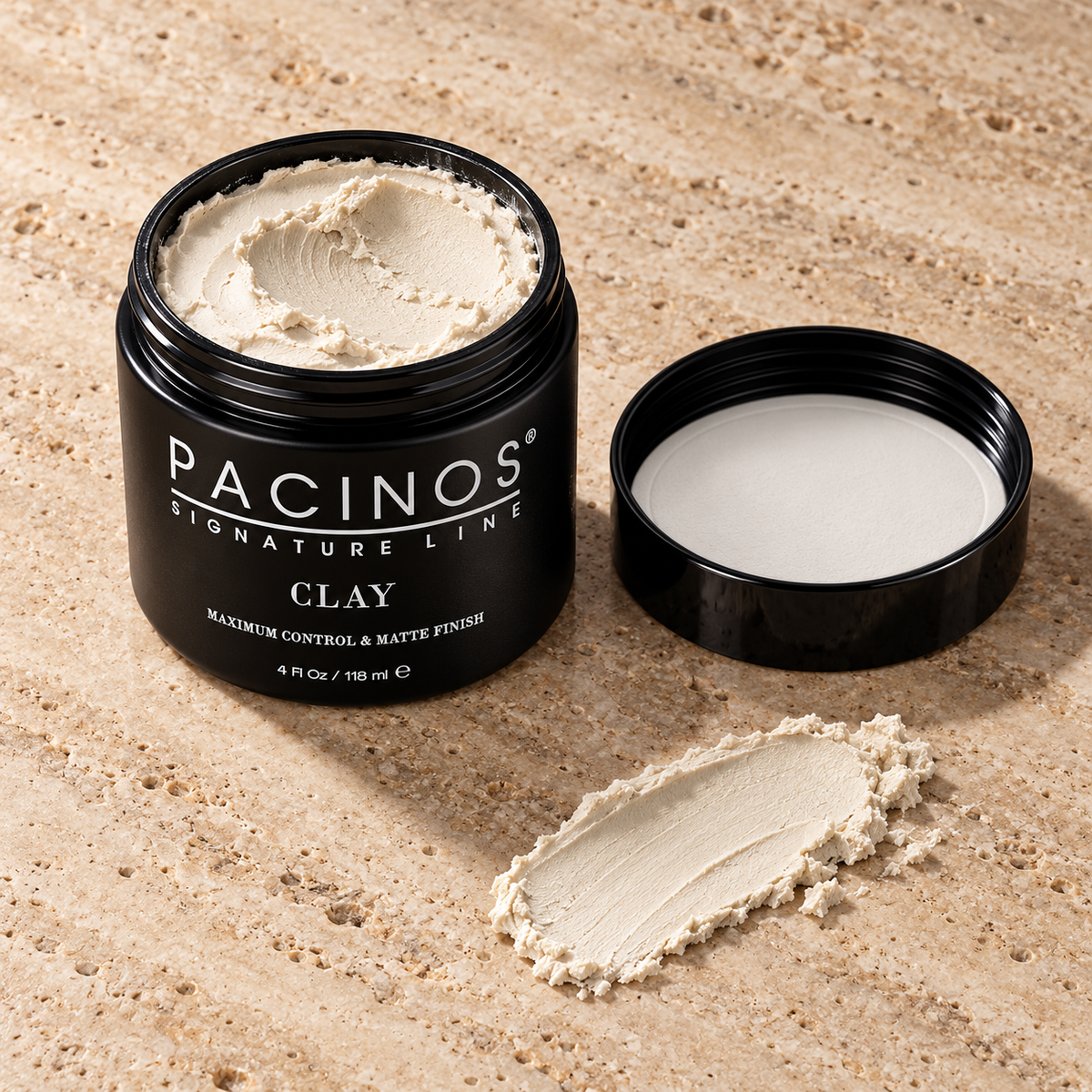 Open jar of Pacinos Clay with a swipe of the matte clay on travertine