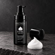 Pacinos Curl Mousse bottle beside a dollop of white foam on dark stone